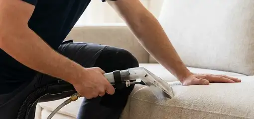 Professional upholstery cleaner deep-cleaning a fabric sofa with a handheld extraction tool, Eugene, OR.